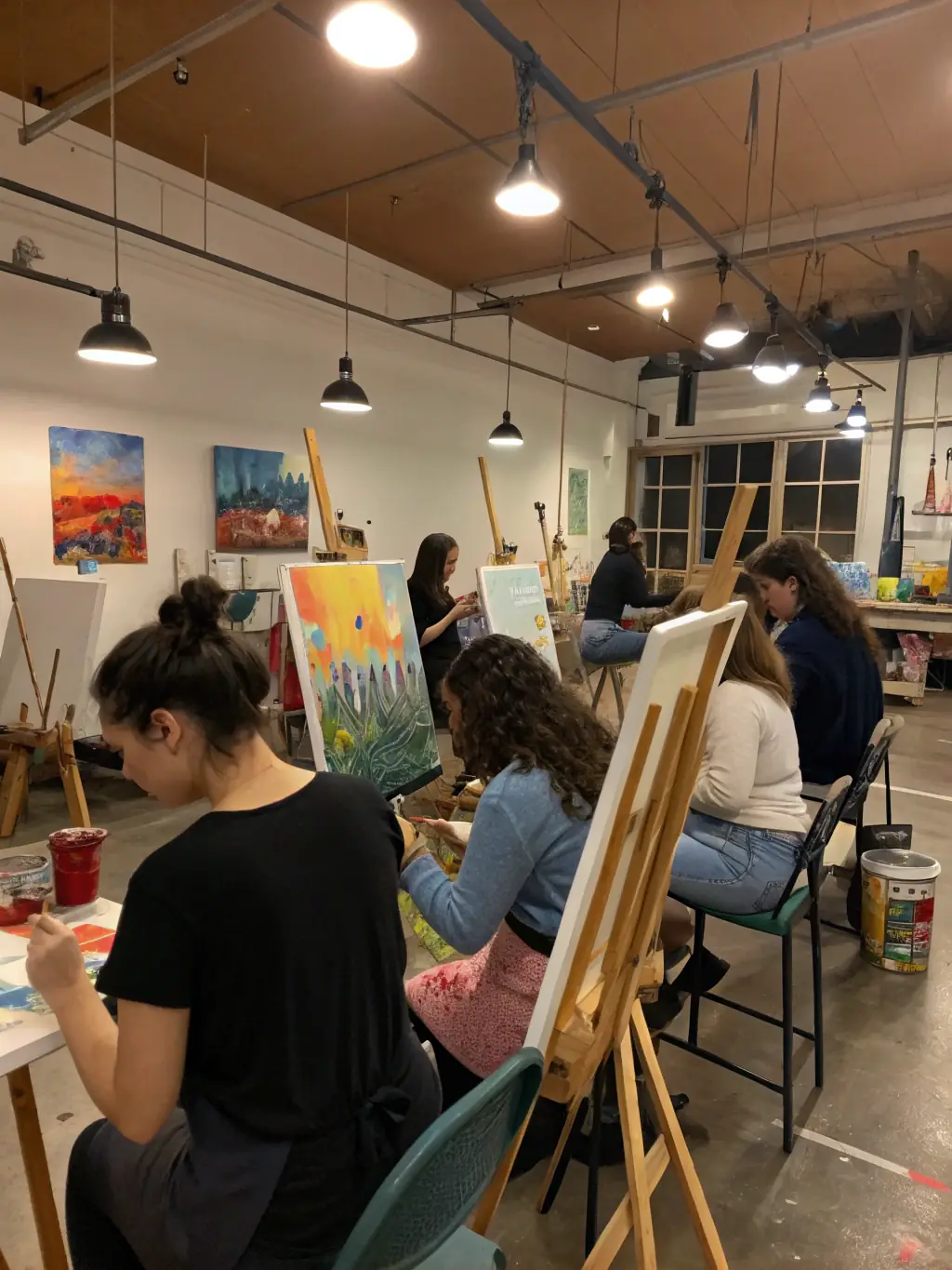 A photograph of a visual arts workshop in progress, with participants creating artwork and an instructor providing guidance, emphasizing the diverse artistic activities supported by QUARTIERS LIBRES.